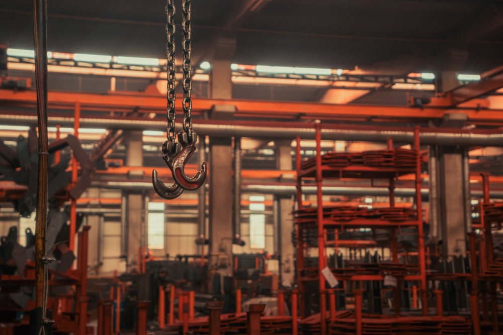 Fabrika salonunda asılı vinç kancası ve üretim hattı