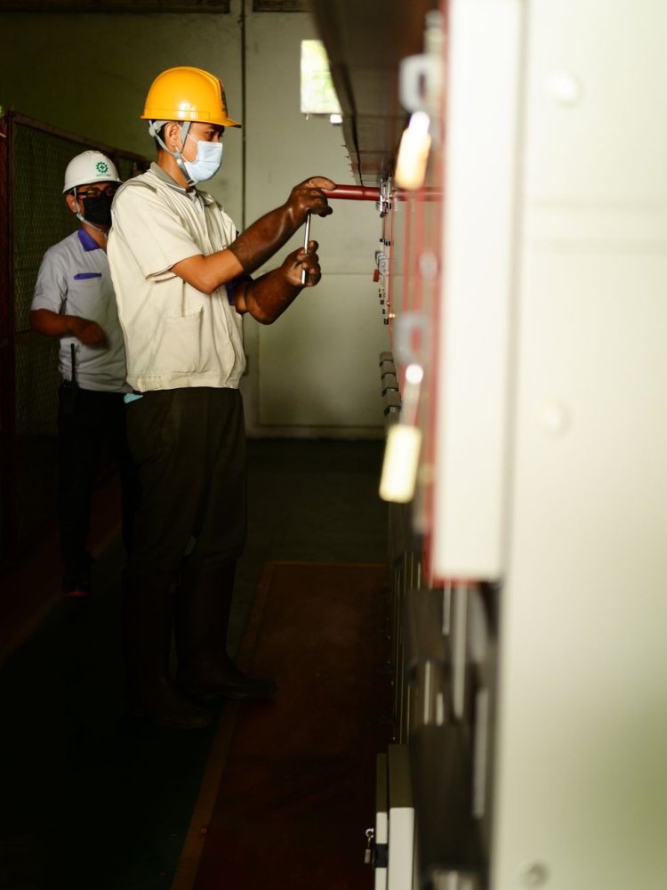 Eski şalt panoları üzerinde çalışan iki elektrikçi